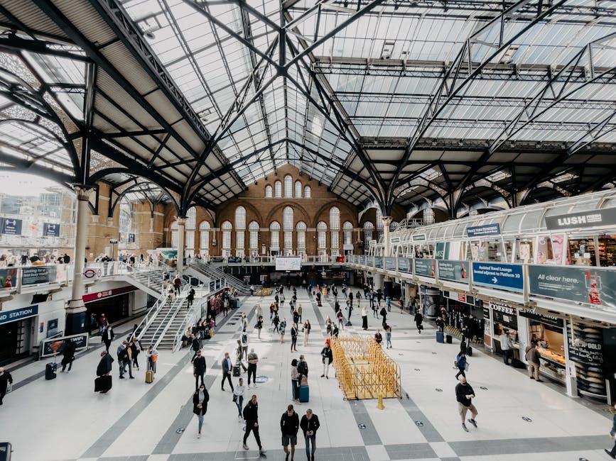 An empty, modern Bermondsey station entrance showcasing polished, reflective ceramic floor tiles and stainless steel ticket barriers arranged in a row, illuminated by bright overhead LED lighting in a